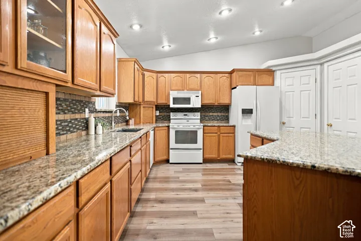 Kitchen featuring wood cabinetry, light-colored countertops, a tile backsplash, wood-finish flooring, and recessed lighting