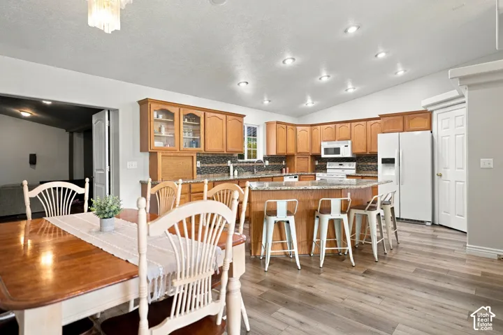 Kitchen featuring wood-finish flooring, recessed lighting, wood cabinetry, stone countertops, and a tile backsplash