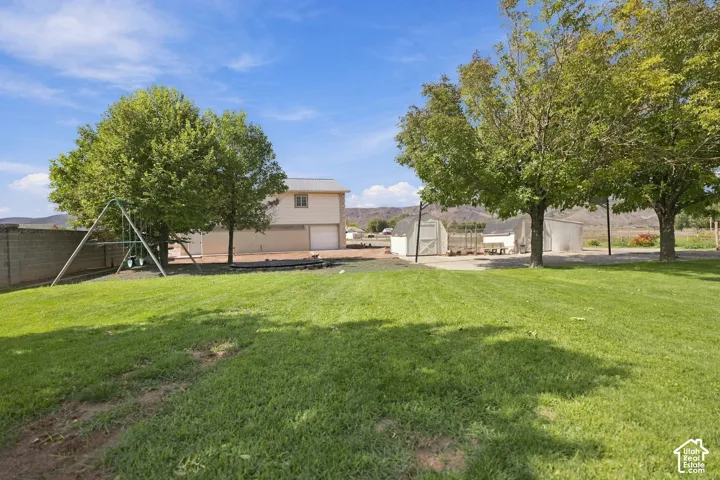 Expansive grounds featuring a manicured lawn with mature shade trees, detached storage structure, and fenced perimeter