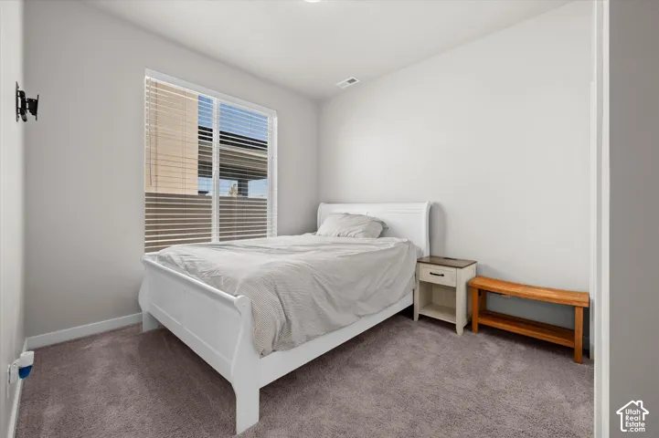 Carpeted room with a large window featuring horizontal blinds