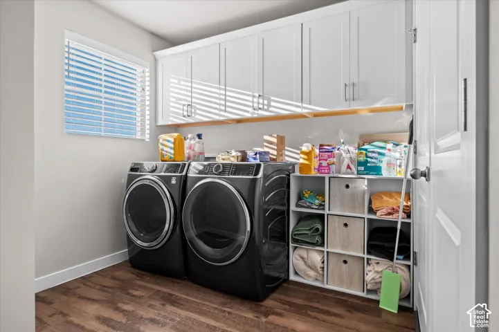 Laundry area featuring wood-finish flooring, white cabinetry with silver hardware, and a window with horizontal blinds