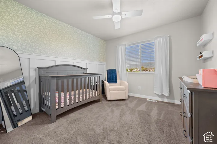 Carpeted room featuring a ceiling fan, window with blinds, and white board and batten wall paneling