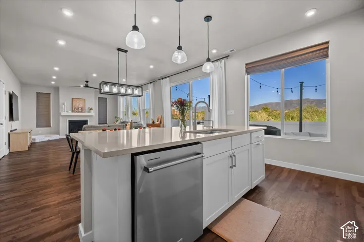 Kitchen island with an undermount sink, stainless steel dishwasher, and light-toned countertop