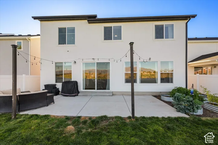 Rear exterior with a concrete patio, multiple windows, and a sliding glass door