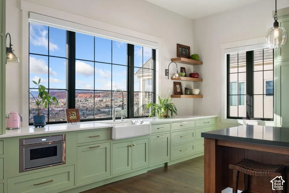 Kitchen featuring a large picture window, light green cabinetry, white countertops, a built-in microwave, and a farmhouse sink