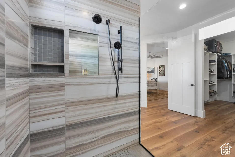 Full-height glass shower enclosure with striped wall tile, integrated shower niche with mosaic tile, and a matte black shower system