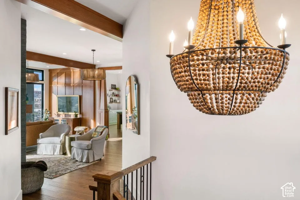 Two-tiered beaded chandelier, wood-finish flooring, exposed wood beams, and built-in wood paneling