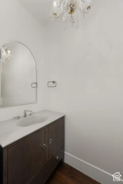 Crystal chandelier lighting a wood-finish vanity with an integrated sink, polished chrome faucet, and an arched mirror