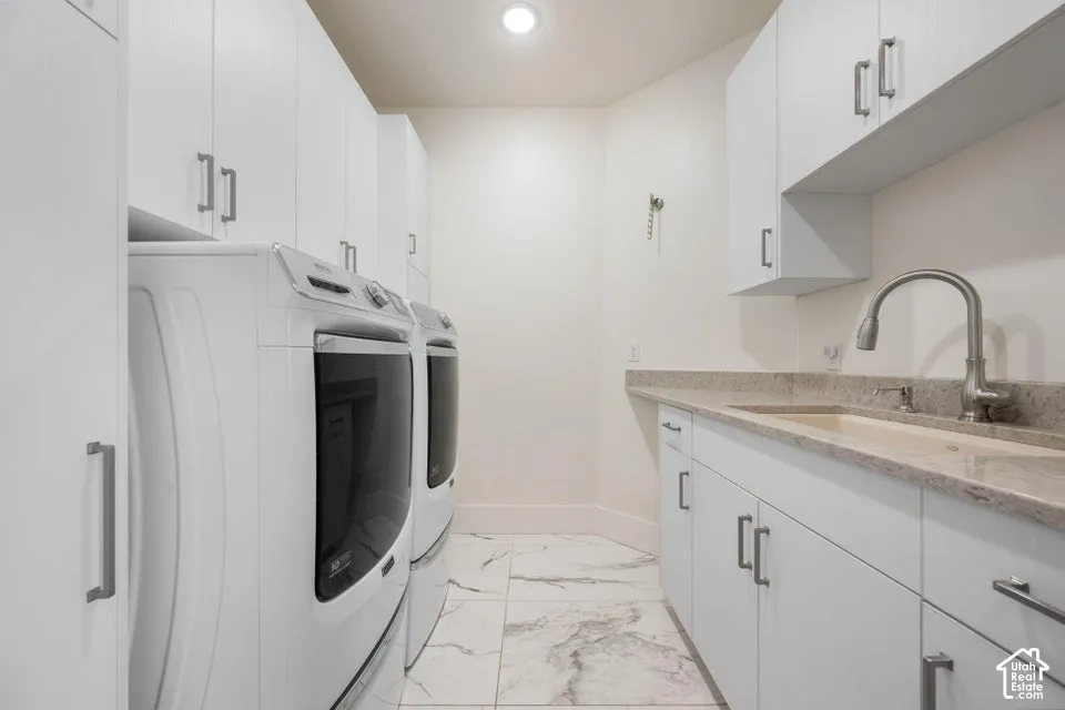 Full-height cabinetry, tile flooring, built-in sink with gooseneck faucet, and integrated washer and dryer
