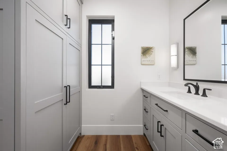 Built-in white shaker cabinetry, black framed window, wood-finish flooring, white countertop, and a black framed mirror