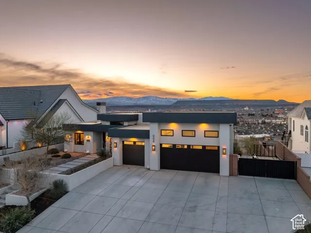 Modern architectural exterior featuring multiple garages, a gated entry, and a multi-level concrete driveway