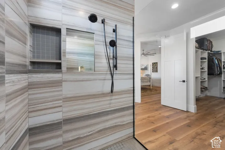 Full-height glass shower enclosure with striped wall tile, integrated shower niche with mosaic tile, and a matte black shower system