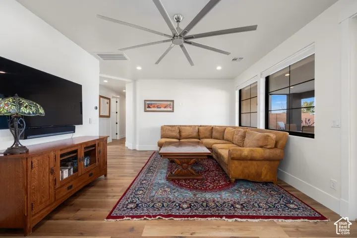 Wood-finish flooring, recessed lighting, and a large ceiling fan with multiple blades
