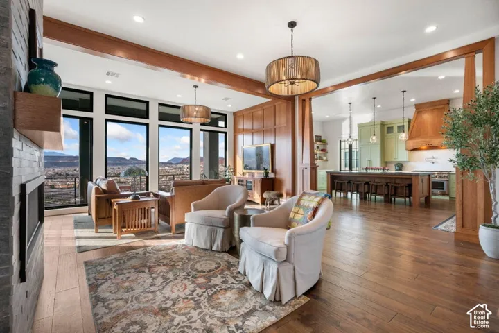 Spacious living area featuring expansive windows, wood-finish flooring, a stone-clad fireplace, and recessed lighting