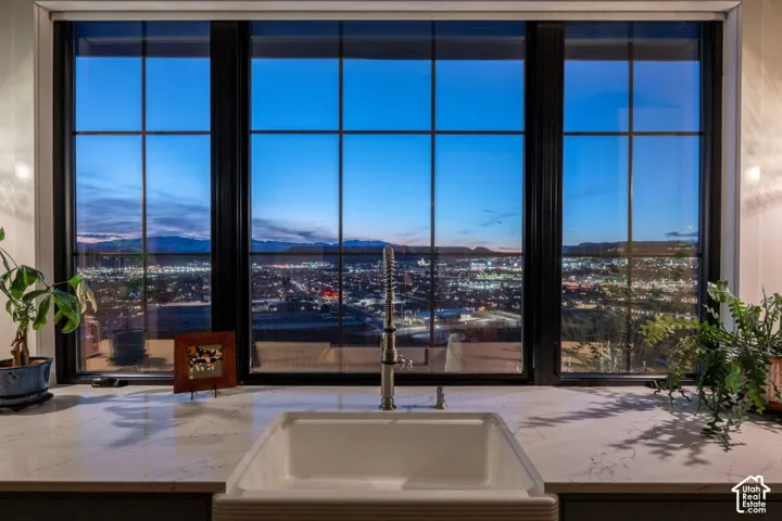 Large multi-pane window with dark frames, white farmhouse sink, gooseneck faucet, and light-toned countertop