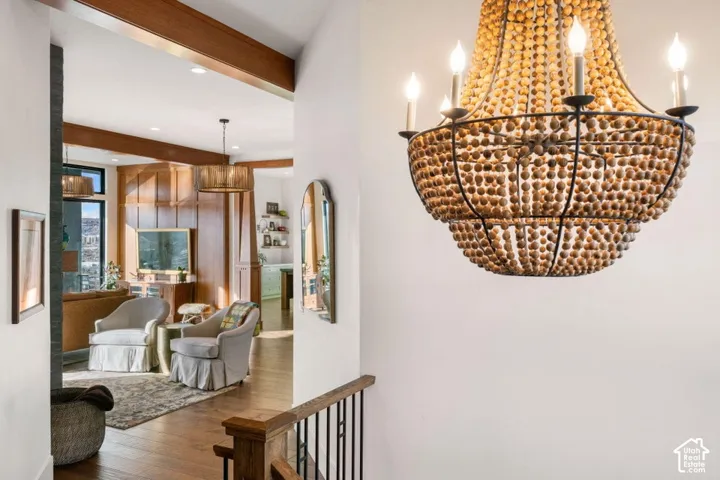 Two-tiered beaded chandelier, wood-finish flooring, exposed wood beams, and built-in wood paneling