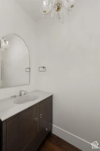 Crystal chandelier lighting a wood-finish vanity with an integrated sink, polished chrome faucet, and an arched mirror