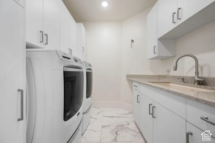 Full-height cabinetry, tile flooring, built-in sink with gooseneck faucet, and integrated washer and dryer