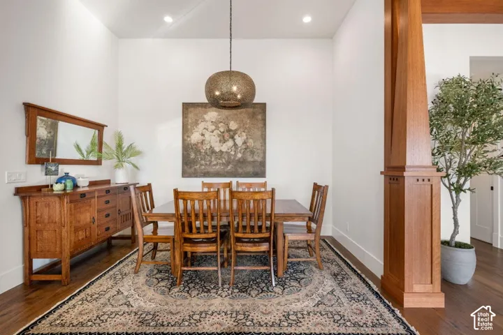 Formal dining room showcasing warm wood-finish flooring, a neutral patterned area rug, and rich wood cabinetry with integrated storage