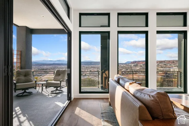 Expansive glass sliding door system, large pane windows, wood-finish flooring, and a covered outdoor balcony