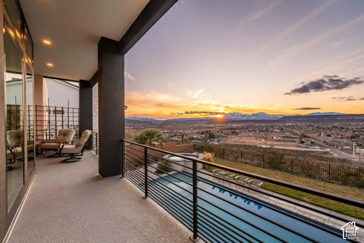 Upper-level patio with dark columns, recessed lighting, and a metal horizontal-bar railing
