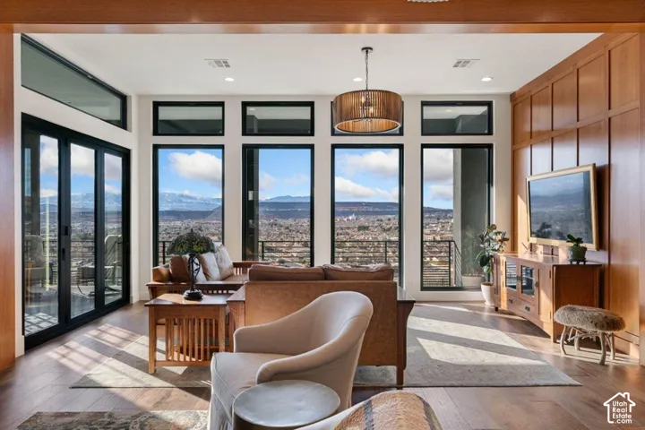 Expansive windows with transom panels, wood-finish flooring, a contemporary drum pendant light fixture, and wood-paneled wall