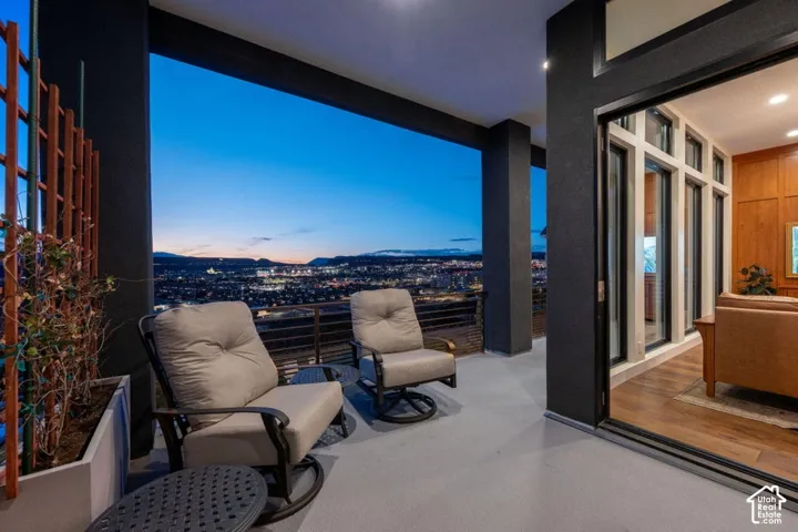 Covered outdoor balcony with a concrete floor, dark support columns, and a metal railing