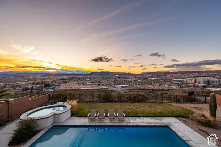 In-ground swimming pool with integrated spa, expansive paver decking, and a distinct mountain backdrop