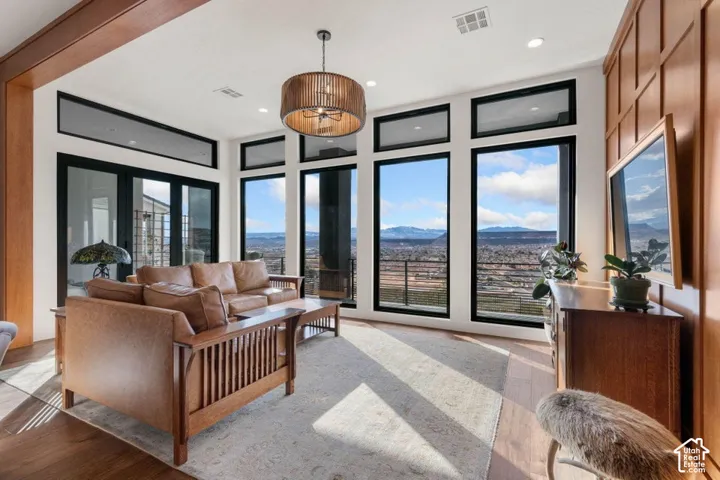 Expansive windows with transom panels, rich wood-finish flooring, recessed lighting, and a decorative pendant light fixture