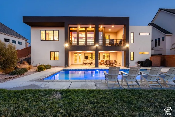 Modern exterior with a rectangular swimming pool, concrete patio, and upper-level covered balcony
