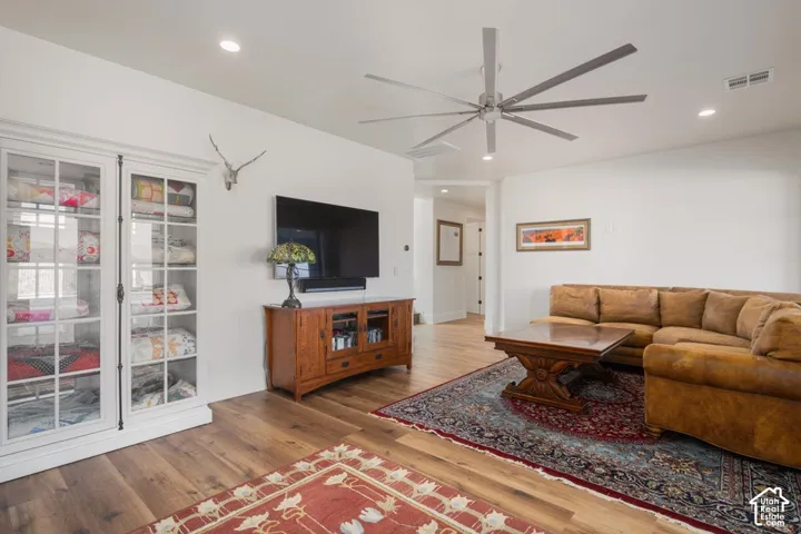 Spacious living area featuring wood-finish flooring, recessed lighting, and a large ceiling fan