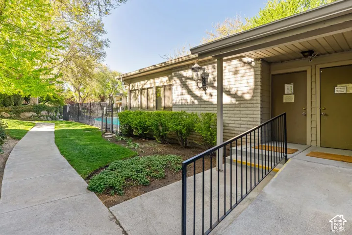 Brick exterior building featuring a covered entryway, black metal handrail, and concrete pathway