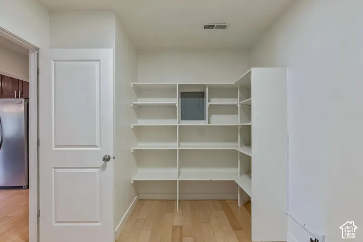 Walk-in pantry featuring light wood-finish flooring and extensive built-in shelving