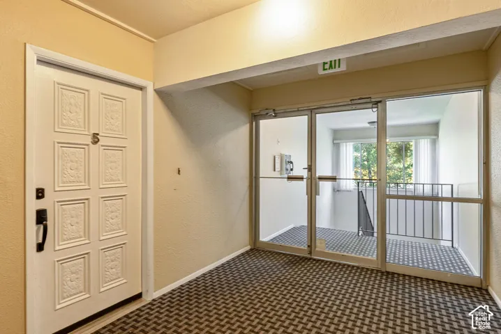 Textured entrance door with dark hardware, pattern carpet flooring, and glass-paneled double doors