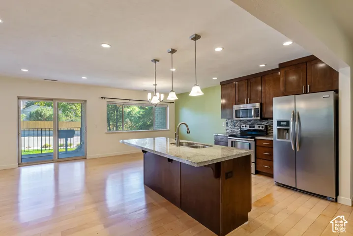 Kitchen featuring rich wood-finish cabinetry, stainless steel appliances, and a central island with a light-toned countertop