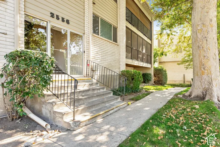 Building exterior with brick and siding facade, concrete entry stairs with metal railings, and a concrete pathway
