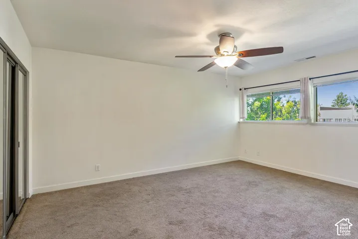 Wall-to-wall carpeting, multiple windows, and a ceiling fan with integrated lighting