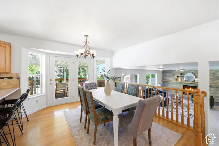 Bright dining area with wood-finish flooring, a white dining table with seating for six, and a brass chandelier overhead