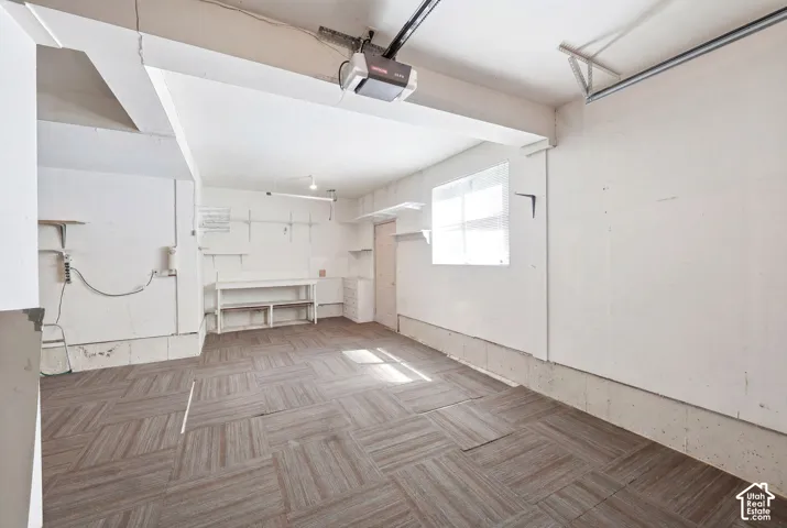 Garage space featuring a patterned tile floor, built-in shelving, workbench, and window