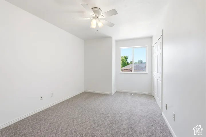 Recessed ceiling light, ceiling fan, white trim, sliding closet doors, and light gray carpet