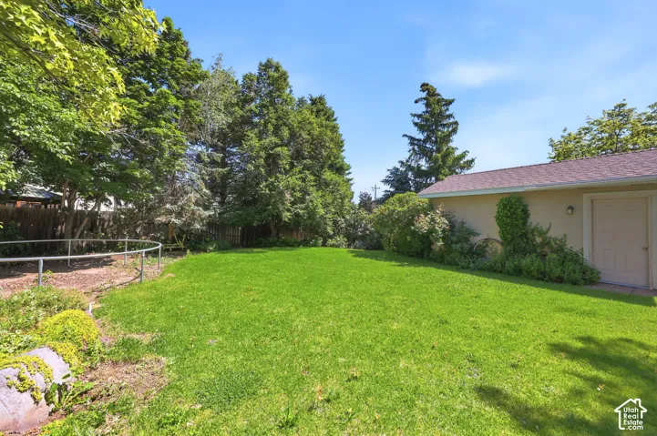 Expansive lawn with mature trees and a fenced perimeter