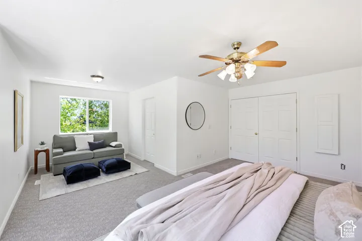 Wall-to-wall carpeting, window with natural light, ceiling fan with integrated lighting, and two-door closet