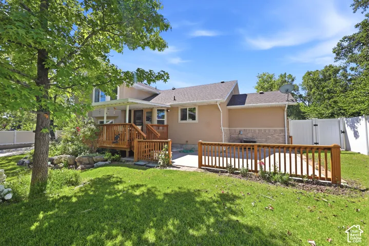 Expansive backyard featuring a manicured lawn, a multi-level wood deck, a covered patio area, and a private fenced perimeter