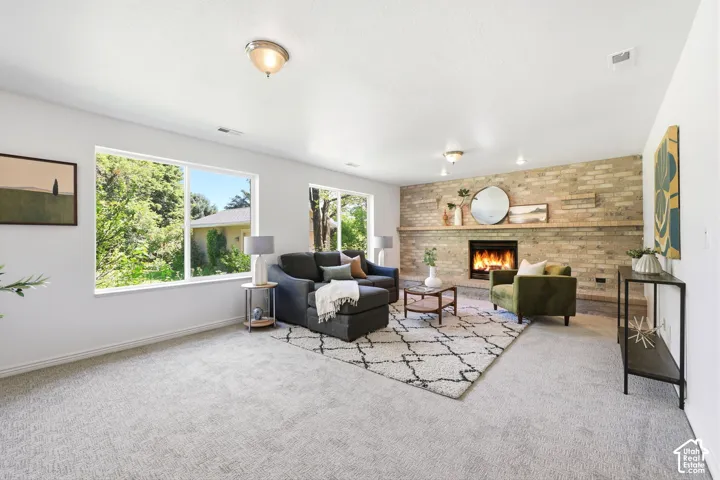 Expansive living area with large windows, light-colored carpeting, a brick-faced fireplace, and recessed lighting