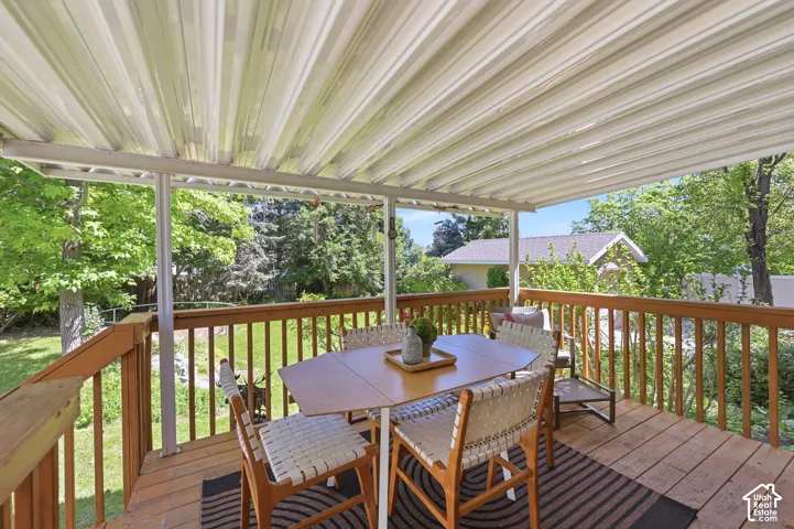 Spacious covered deck featuring wood decking, wood railings, and a corrugated metal ceiling