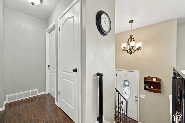 Wood-finish flooring, white paneled doors, and a decorative chandelier with frosted glass shades