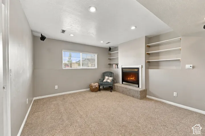 Recessed lighting, built-in shelving, a fireplace with a hearth, and a window with blinds