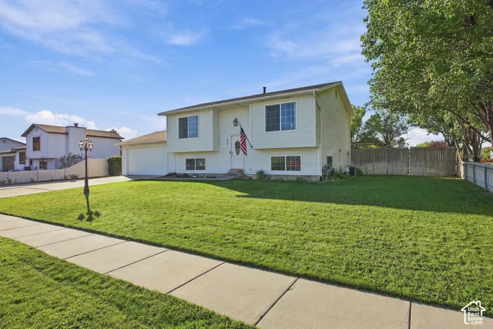 Two-story residence with white siding, an attached garage, a manicured front lawn, and a sidewalk