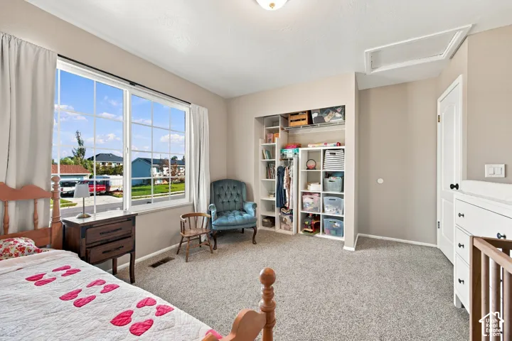 Recessed lighting, large window with grid pattern, neutral wall color, built-in closet shelving, and textured carpet flooring