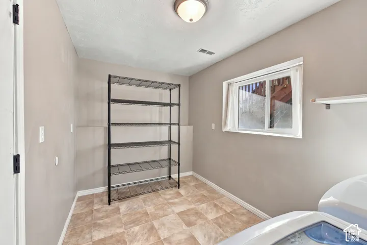 Tiled flooring, overhead flush mount lighting, single window, shelving unit, and neutral wall paint